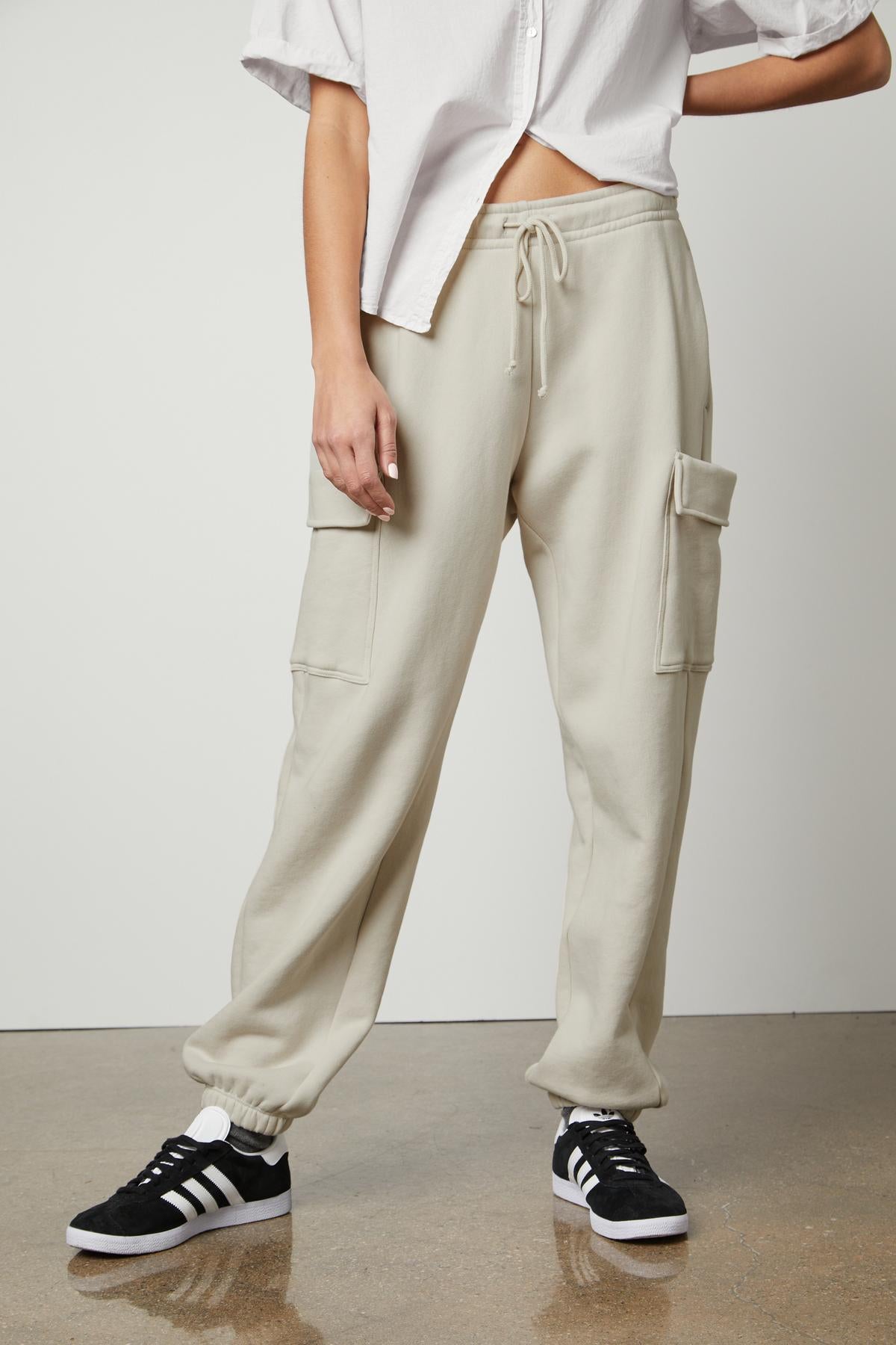 A woman wearing a white t-shirt and Velvet by Graham & Spencer LUMI DRAWSTRING WAIST SWEATPANT for everyday wear while running errands.-35660369395905