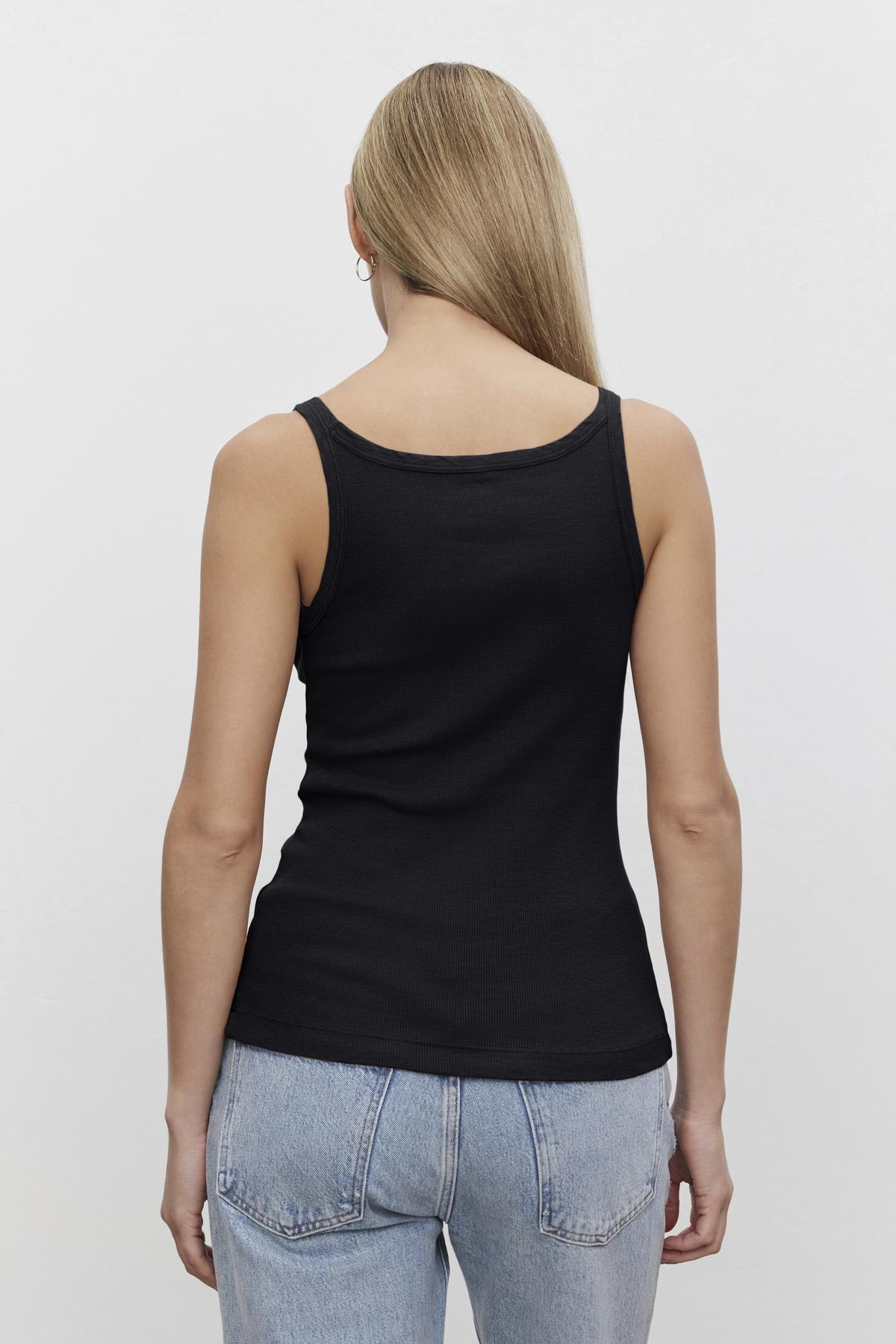 Woman wearing a black Aliza ribbed cotton layering tank from Velvet by Graham & Spencer and blue jeans viewed from the back.-36443834974401