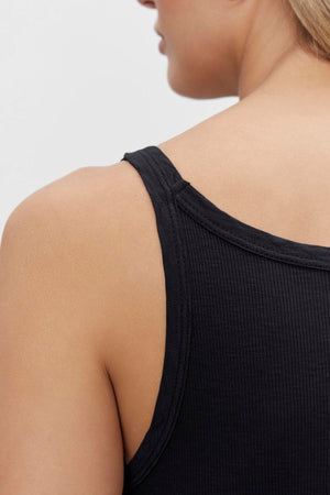 Close-up view of a person's shoulder wearing a black Aliza Ribbed Cotton Layering Tank by Velvet by Graham & Spencer.