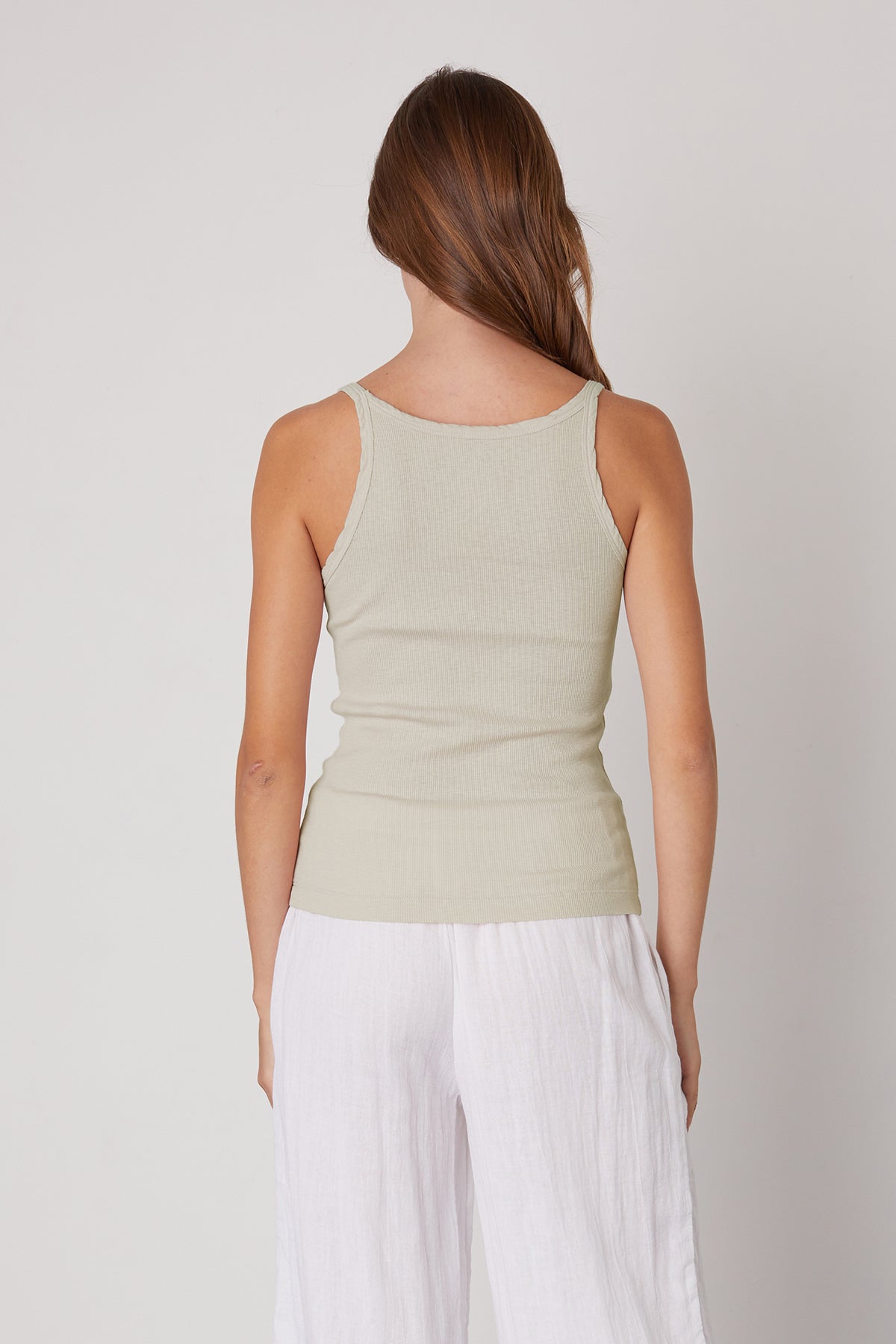 the back view of a woman wearing ALIZA RIBBED COTTON LAYERING TANK by Velvet by Graham & Spencer white pants and a tank top.-35206750437569