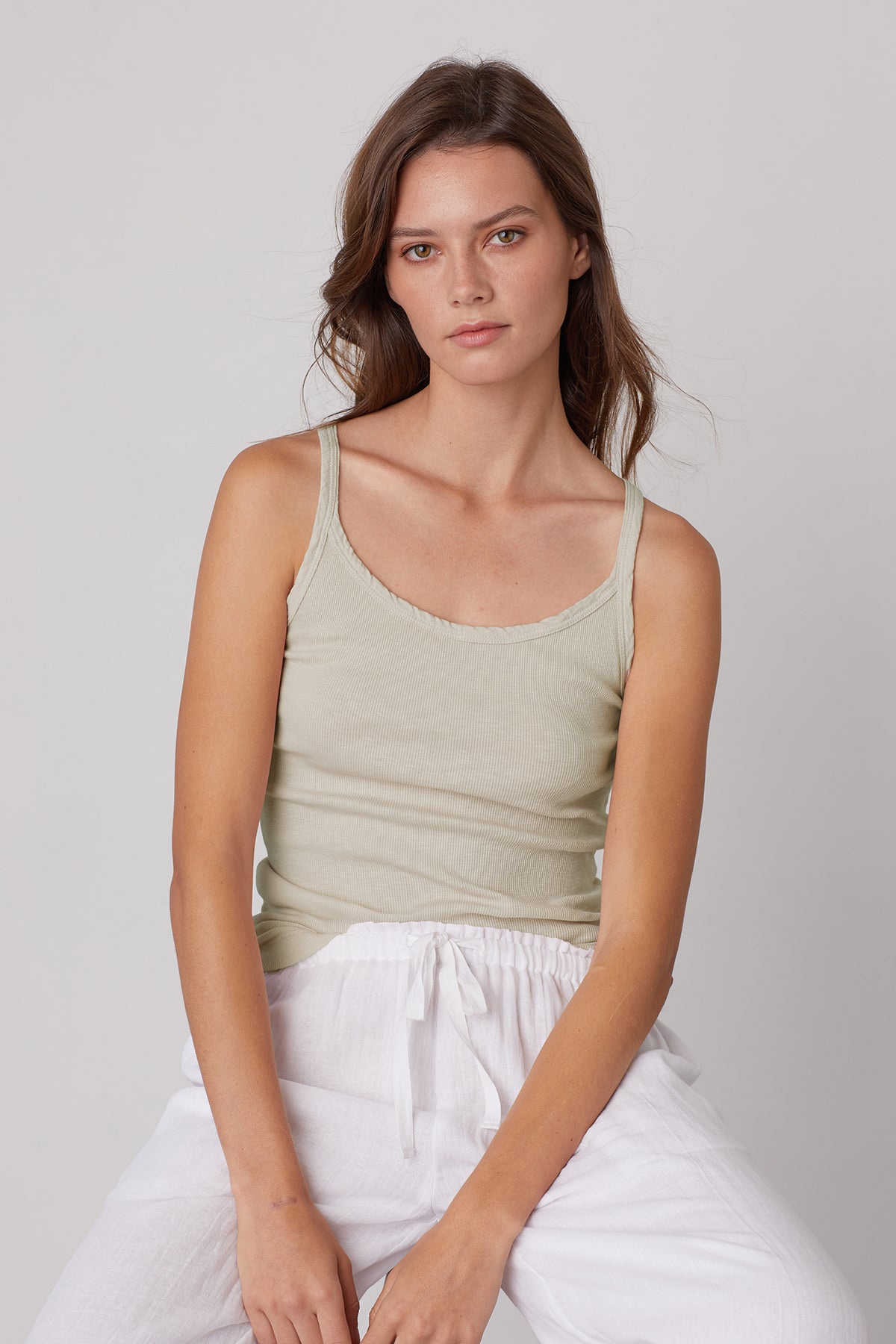 a woman wearing a ALIZA RIBBED COTTON LAYERING TANK by Velvet by Graham & Spencer and white pants.-35206750470337