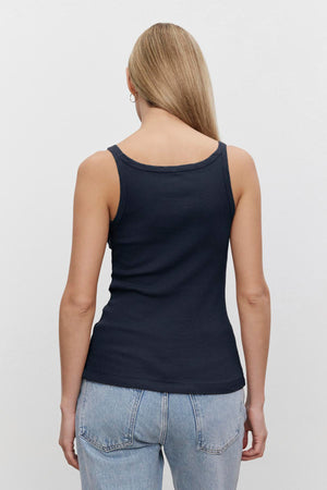 A woman viewed from behind wearing a Velvet by Graham & Spencer ALIZA RIBBED COTTON LAYERING TANK with double-layer straps and light blue jeans, standing against a plain white background.