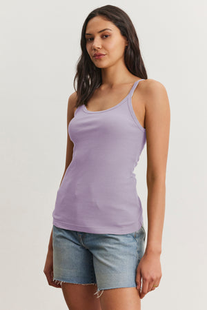Someone wearing a Velvet by Graham & Spencer ALIZA ribbed cotton tank in lavender and denim shorts stands against a plain background.