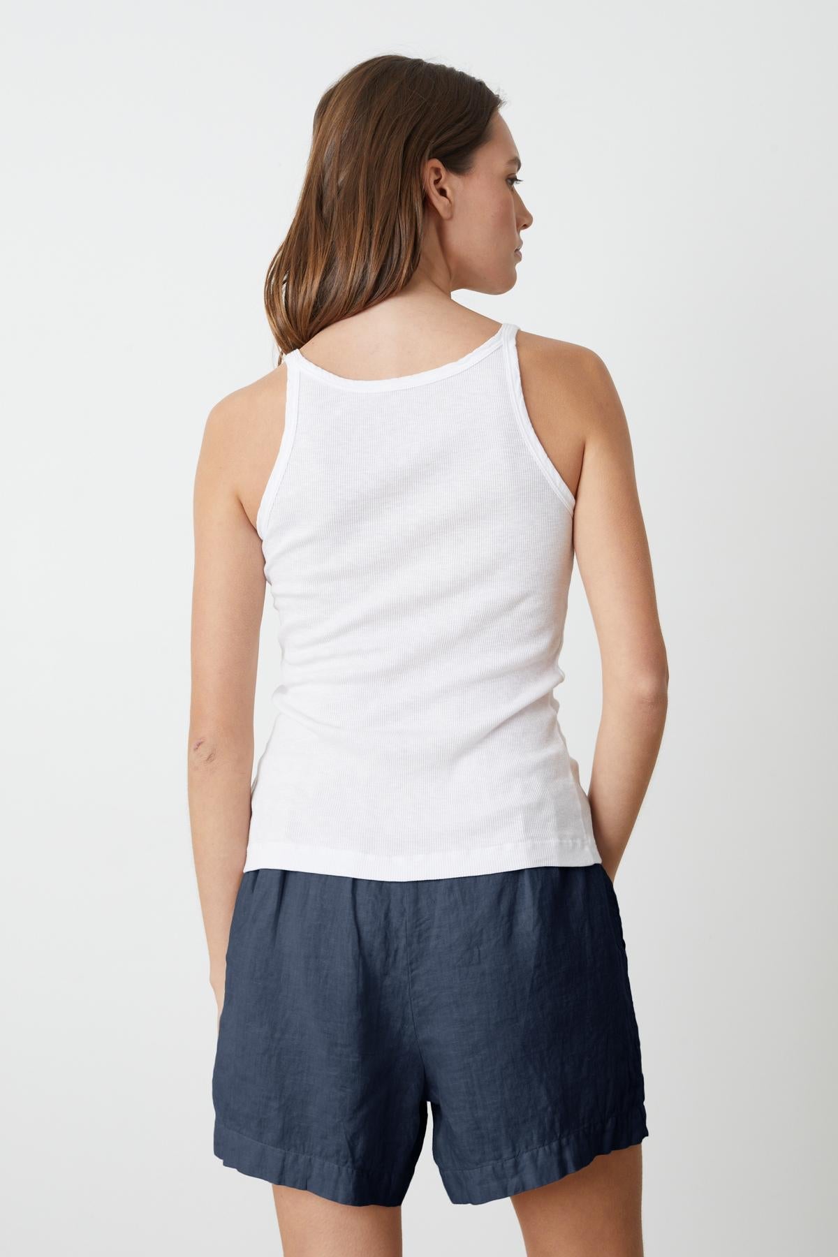 the back view of a woman wearing the Velvet by Graham & Spencer ALIZA RIBBED COTTON LAYERING TANK and navy shorts.-35206750634177
