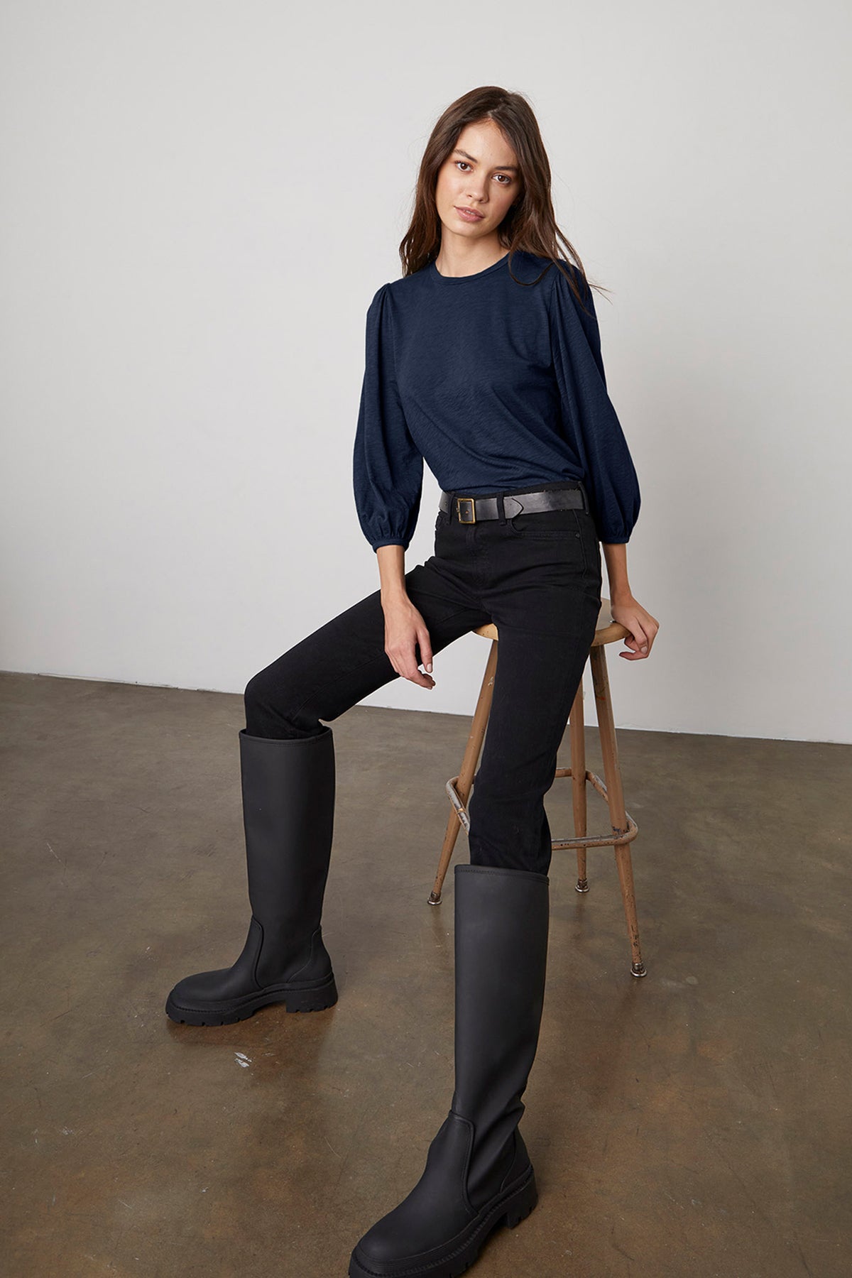   A woman wearing black boots and a blue Velvet by Graham & Spencer ANETTE PUFF SLEEVE TEE shirt. 
