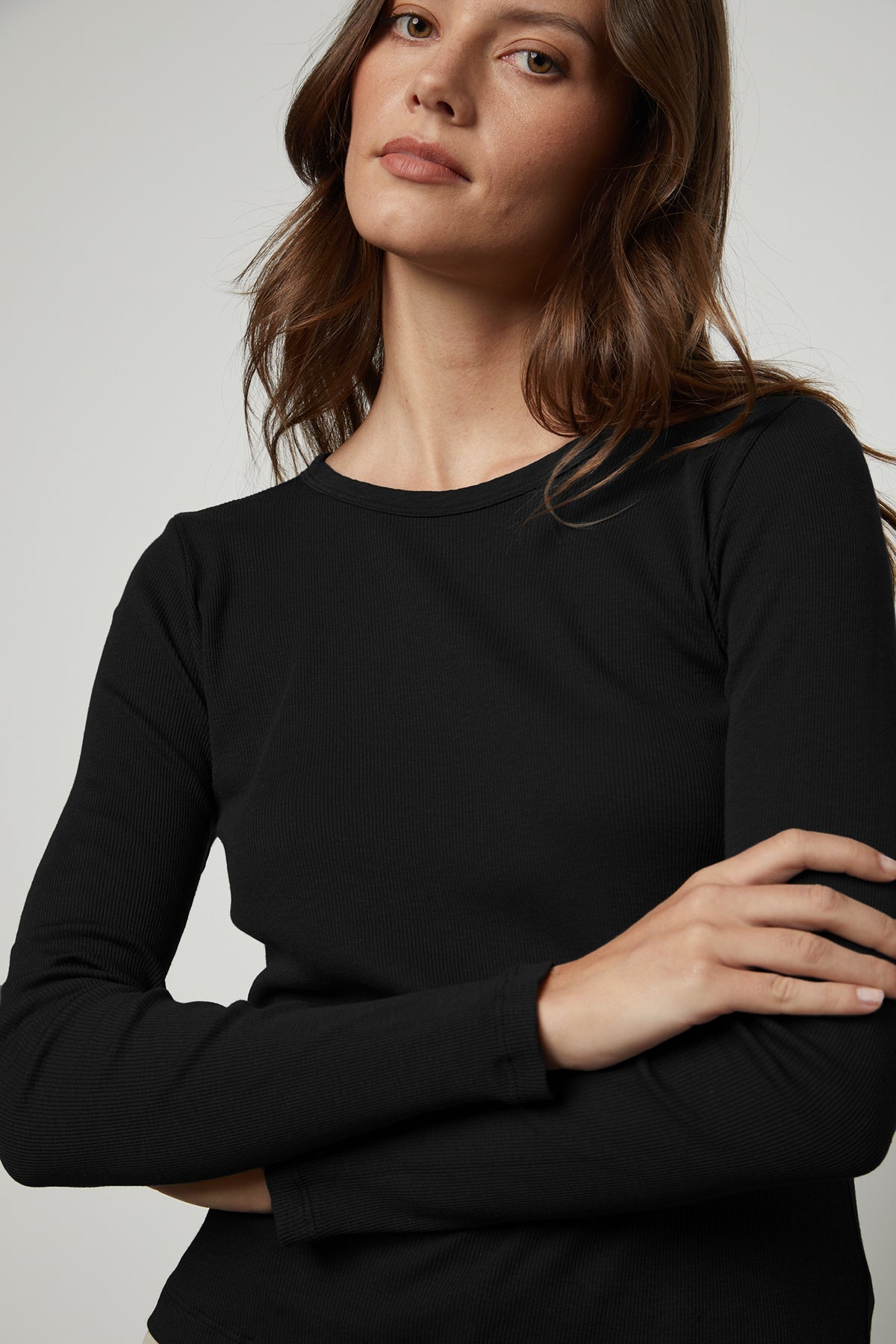 A woman wearing a black long-sleeved Velvet by Graham & Spencer BAYLER RIBBED SCOOP NECK TEE.-35782696894657