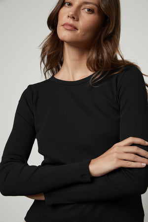 A woman wearing a black long-sleeved Velvet by Graham & Spencer BAYLER RIBBED SCOOP NECK TEE.