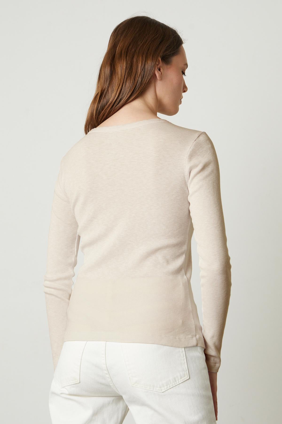 The back view of a woman wearing a Velvet by Graham & Spencer BAYLER RIBBED SCOOP NECK TEE sweater.-35776210501825