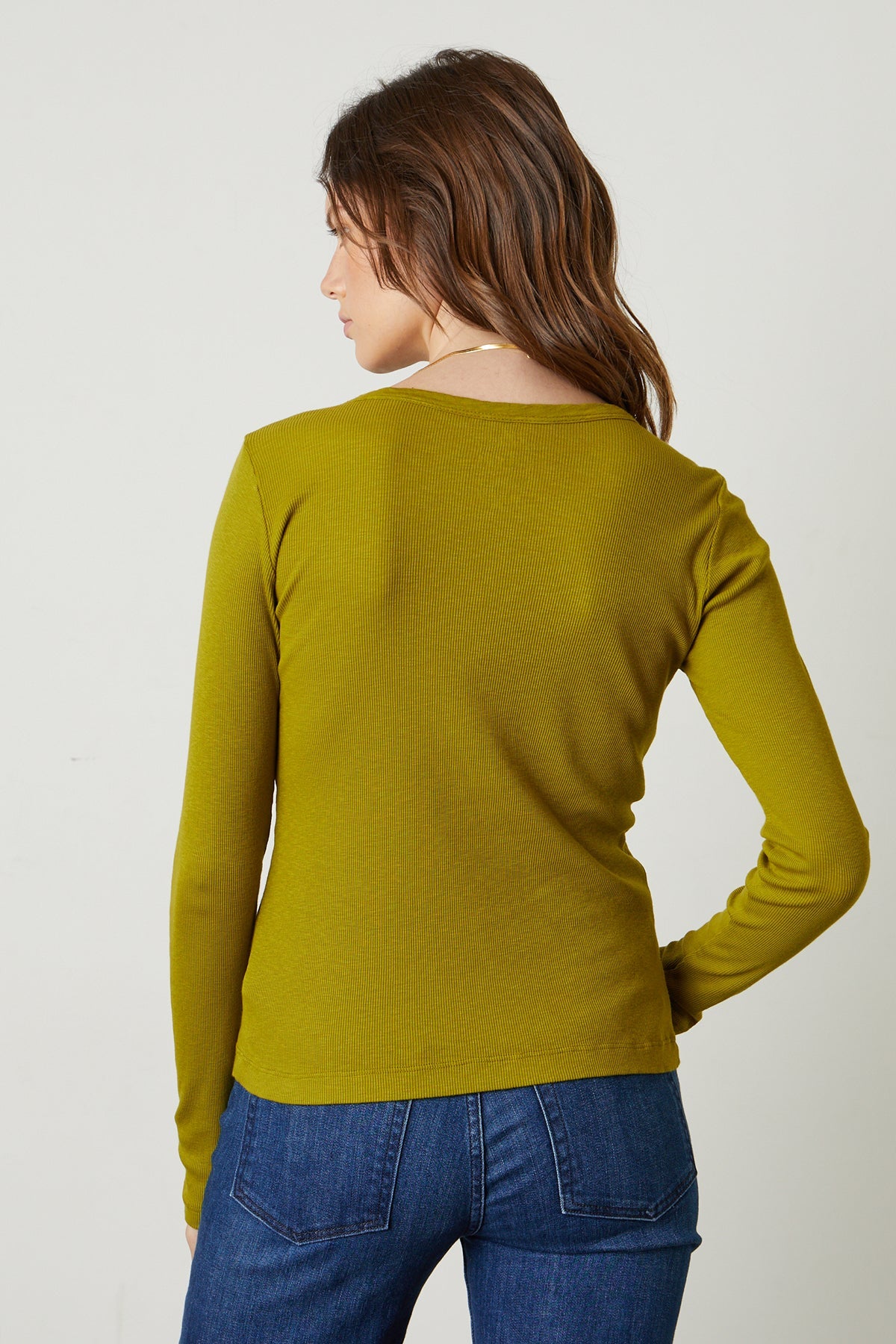 the back view of a woman wearing BAYLER RIBBED SCOOP NECK TEE by Velvet by Graham & Spencer jeans and a long-sleeved top.-26629804753089