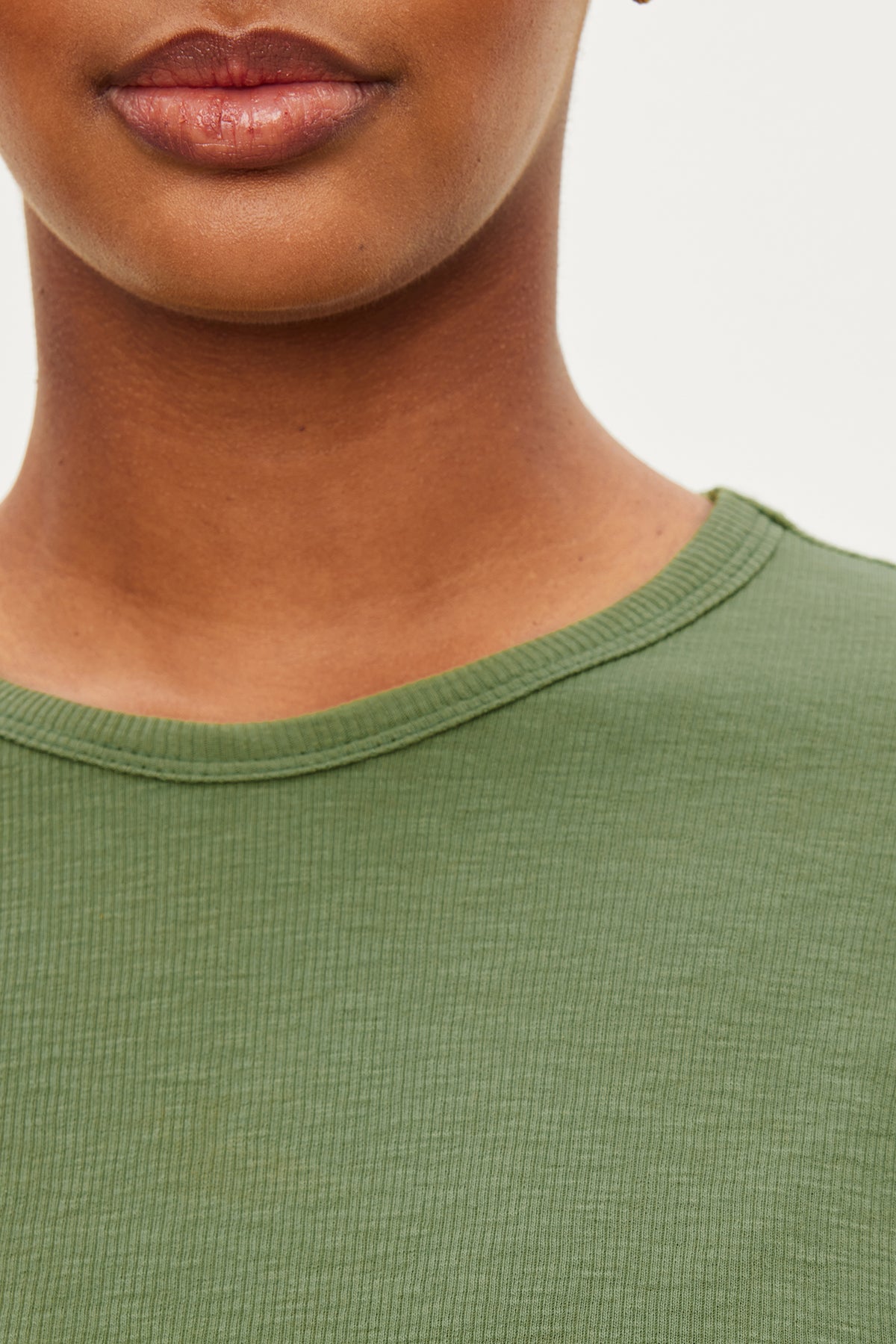   A close up of a woman wearing a cozy green Velvet by Graham & Spencer BRENNY RIBBED CREW NECK TEE. 