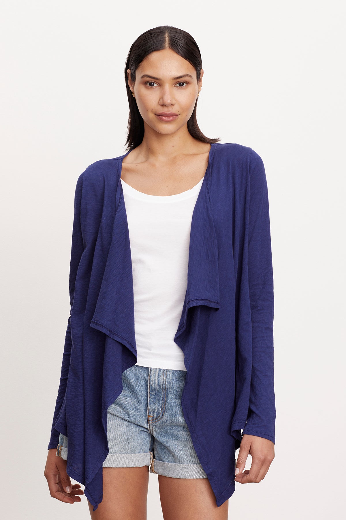 A woman wearing a Velvet by Graham & Spencer CHAMPAGNE OPEN CARDIGAN and shorts.-26743574855873