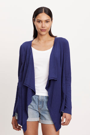 A woman wearing a Velvet by Graham & Spencer CHAMPAGNE OPEN CARDIGAN and shorts.
