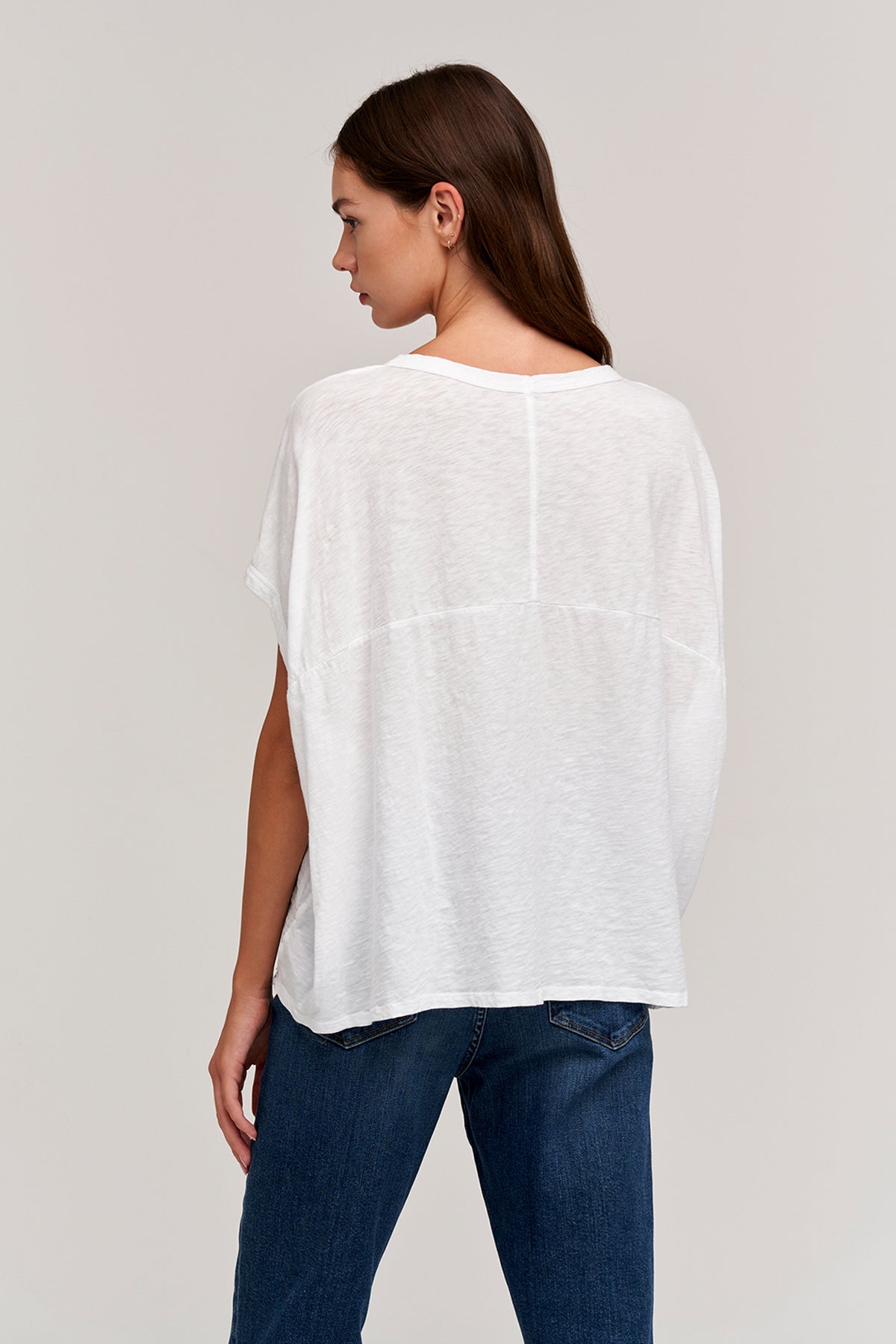 The back view of a woman wearing the Velvet by Graham & Spencer CORA BOXY TEE top and jeans.-26317150191809
