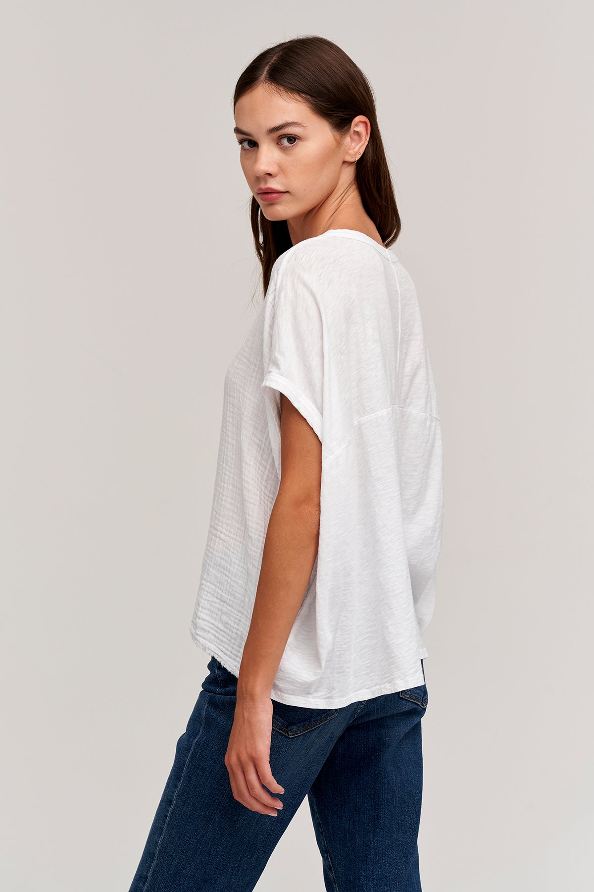   The model is wearing a white CORA BOXY TEE and jeans by Velvet by Graham & Spencer. 