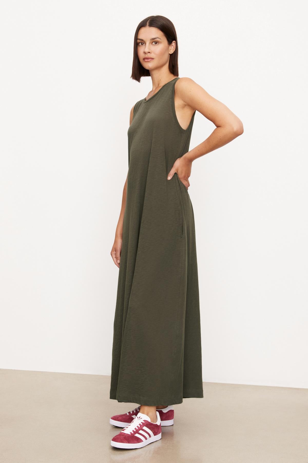 The model is wearing an olive green EDITH SLEEVELESS MAXI DRESS by Velvet by Graham & Spencer with a long silhouette.-35701765800129