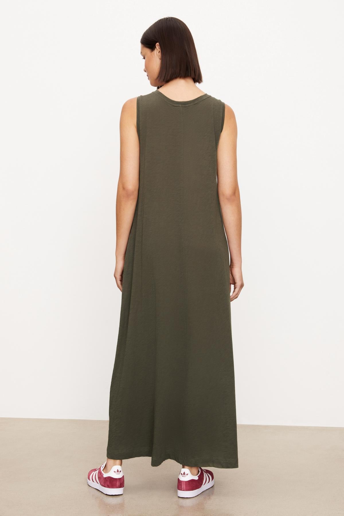   The back view of a woman wearing a green sleeveless Velvet by Graham & Spencer EDITH SLEEVELESS MAXI DRESS. 