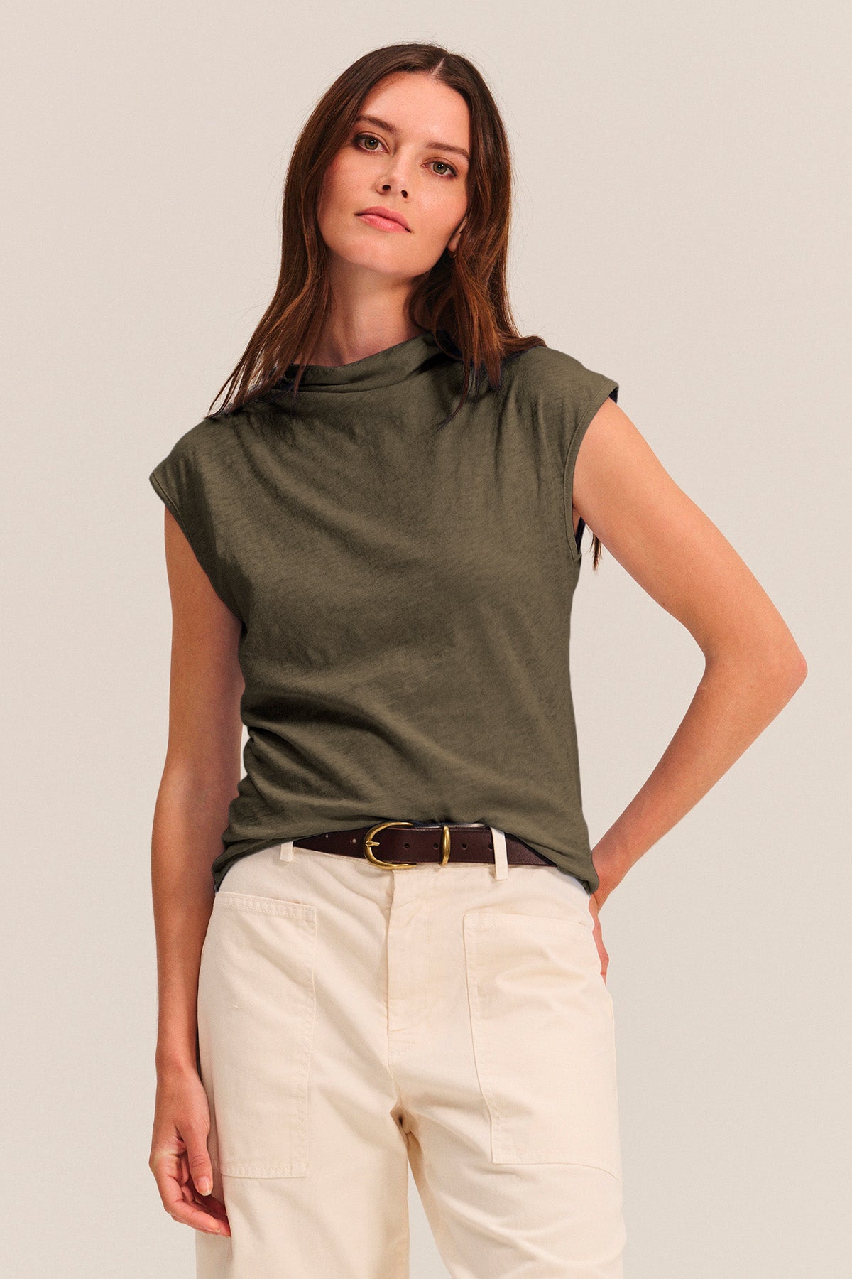 Woman wearing the FLETCHER TEE by Velvet by Graham & Spencer—an olive green sleeveless mock neck top—paired with beige high-waisted pants and a dark brown belt, styled against a plain light background.-41015018684609