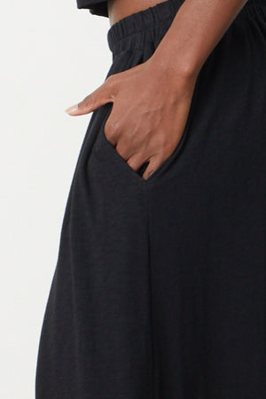 A person wearing a long-sleeved top and pants, the GWEN COTTON SLUB MAXI SKIRT from Velvet by Graham & Spencer.