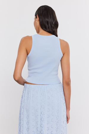 Woman standing with her back to the camera, wearing a light blue Velvet by Graham & Spencer HARLA RIBBED CROPPED TANK TOP and a blue eyelet skirt.