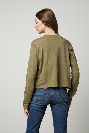 The view of a woman wearing the Velvet by Graham & Spencer HEATHER CREW NECK CROPPED TEE in olive green jeans and a long-sleeved shirt.