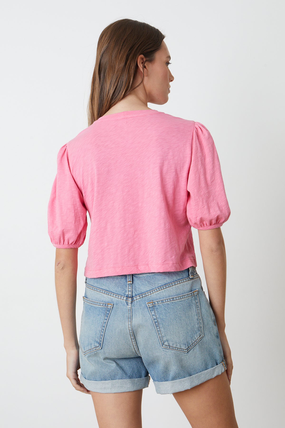   the back view of a woman wearing a Velvet by Graham & Spencer HILARY PUFF SLEEVE CROPPED TEE and denim shorts. 