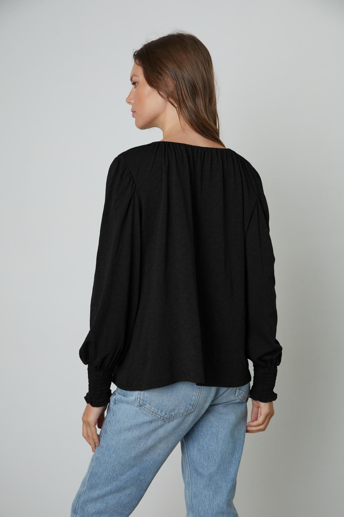 The back view of a woman wearing a Velvet by Graham & Spencer IRINA SPLIT NECK TEE and jeans.-26883564961985