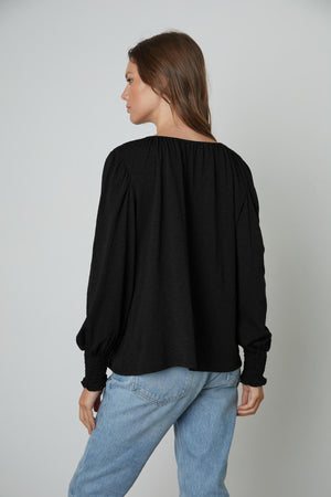 The back view of a woman wearing a Velvet by Graham & Spencer IRINA SPLIT NECK TEE and jeans.