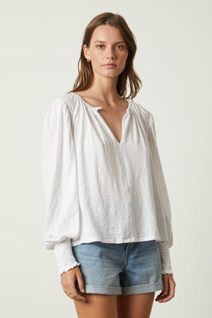 The model is wearing a Velvet by Graham & Spencer IRINA SPLIT NECK TEE with a long sleeve.