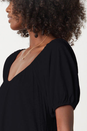 A woman wearing a Velvet by Graham & Spencer JANE SCOOP NECK TIERED DRESS with a puff sleeve.