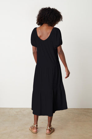 The back view of a woman wearing a JANE SCOOP NECK TIERED DRESS by Velvet by Graham & Spencer.