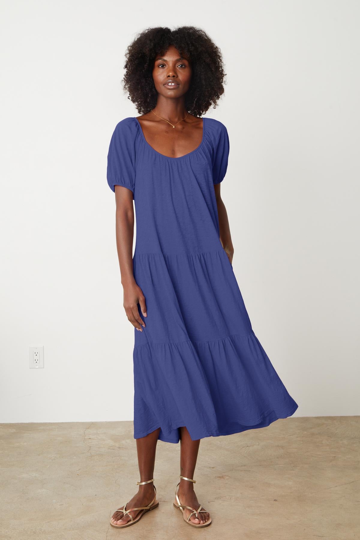   A black woman wearing the JANE SCOOP NECK TIERED DRESS by Velvet by Graham & Spencer. 