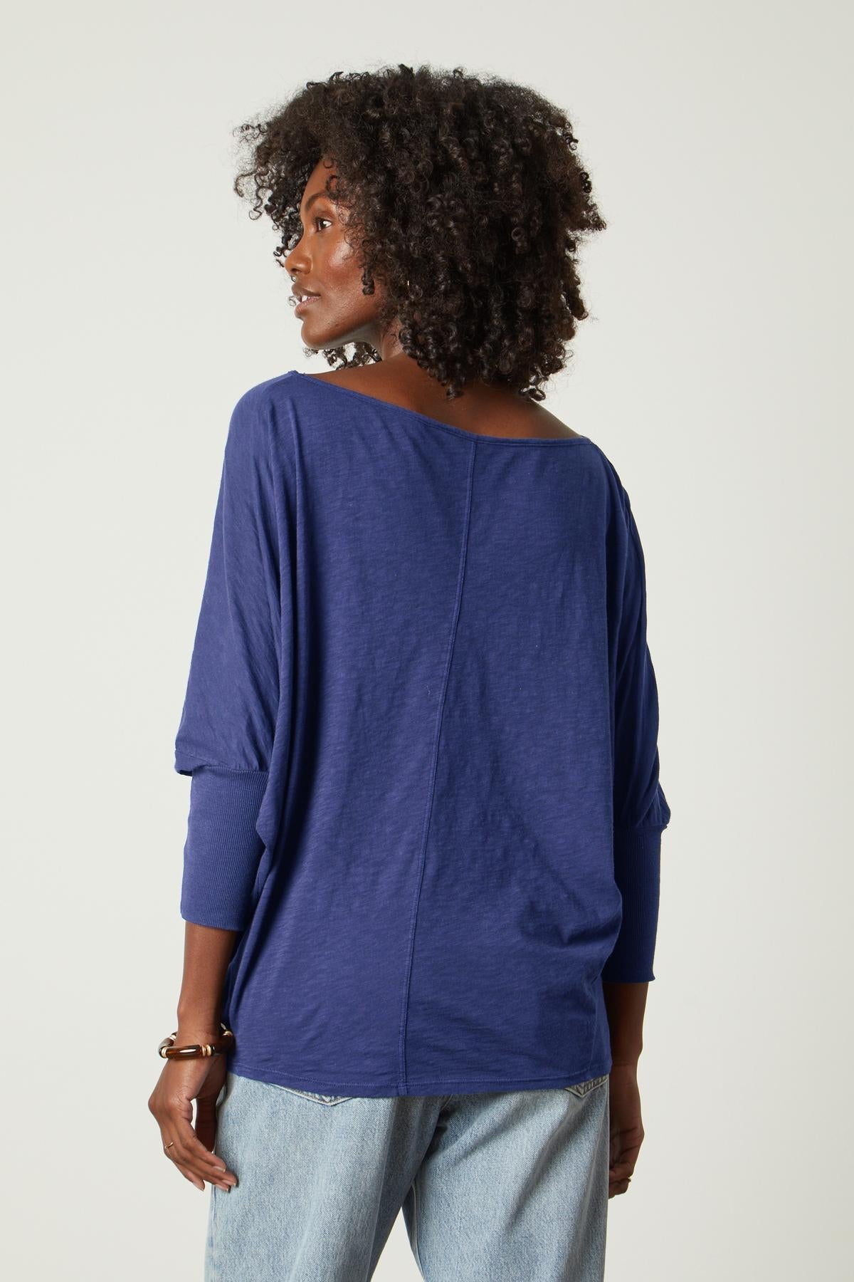   The back view of a woman wearing Velvet by Graham & Spencer jeans and a blue top. 
