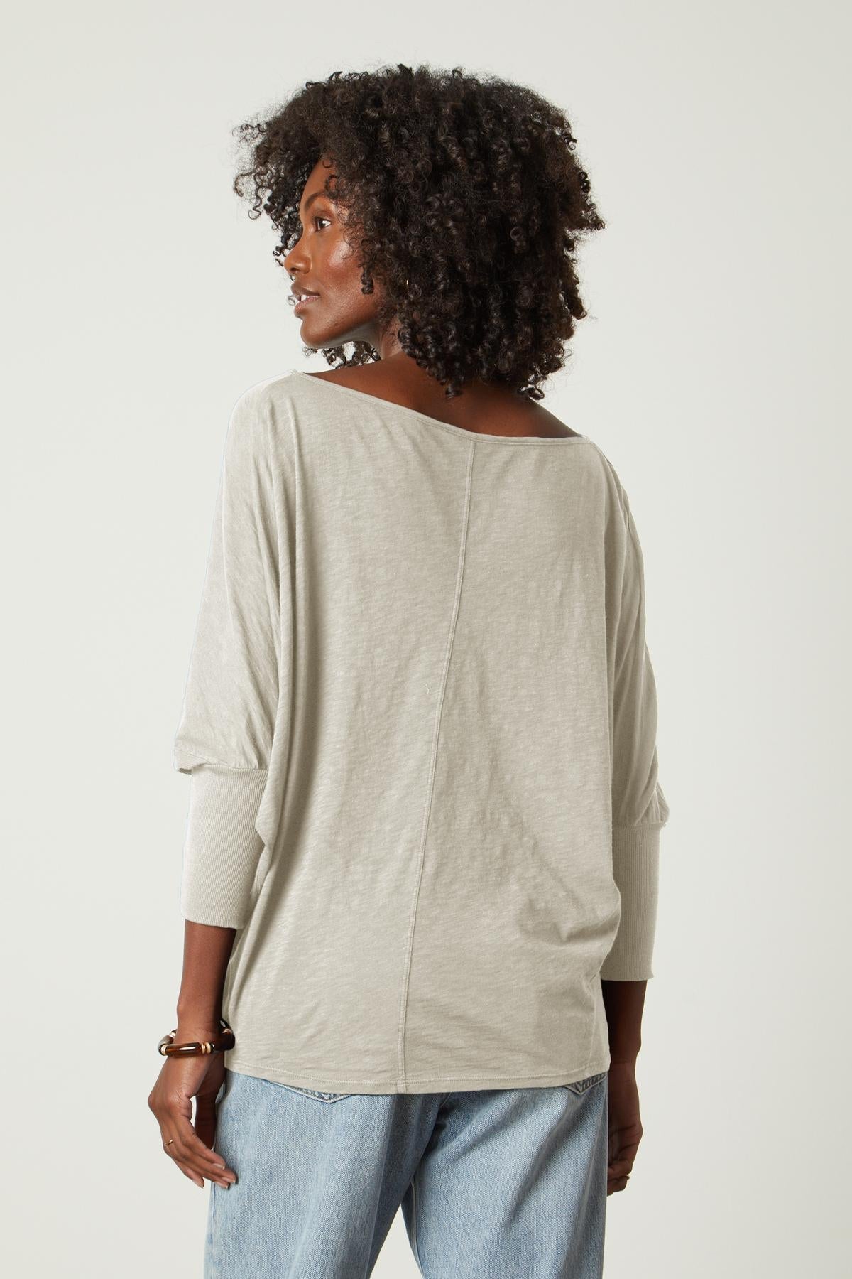   The back view of a woman wearing a Velvet by Graham & Spencer JOSS DOLMAN SLEEVE TEE and jeans. 