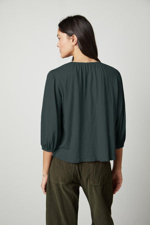 The back view of a woman wearing a Velvet by Graham & Spencer JULIE 3/4 SLEEVE TEE in olive green.