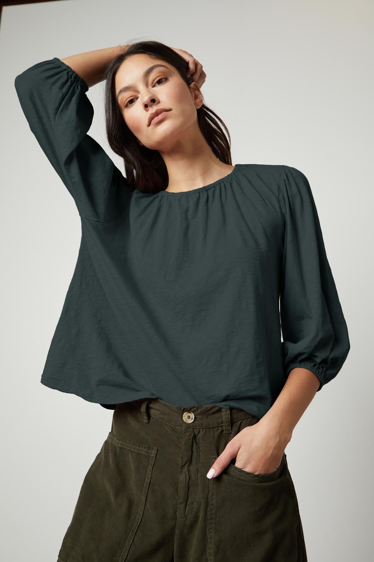   The model is wearing an JULIE 3/4 SLEEVE TEE by Velvet by Graham & Spencer in olive green with puff sleeves. 