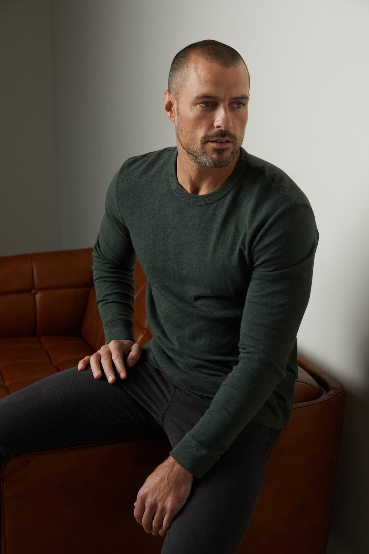   A man sitting on a brown couch in a soft cotton slub knit Velvet by Graham & Spencer Palmer Crew Neck Tee. 