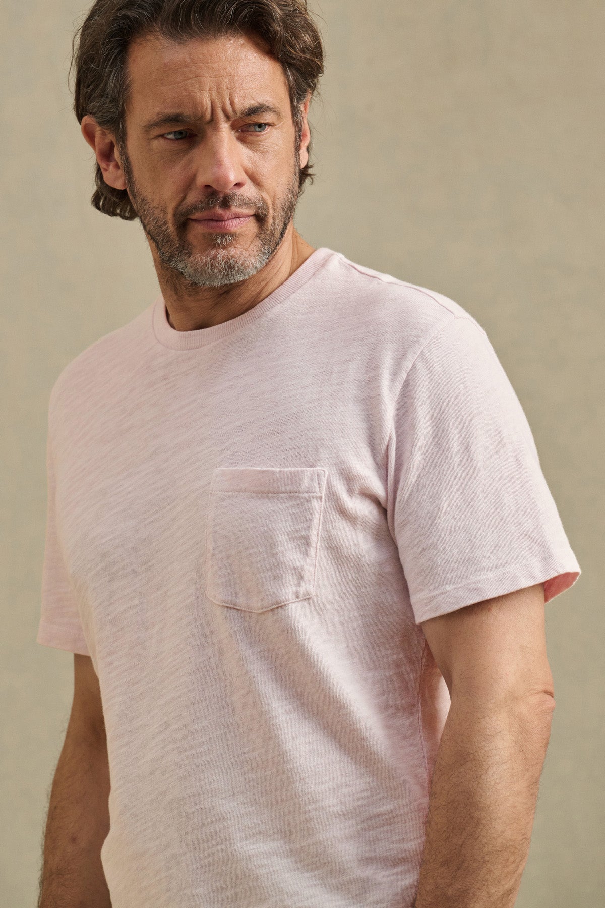 Man with short brown hair and beard wears the PAUL TEE by Velvet by Graham & Spencer, a light pink 100% cotton slub crew neck tee with chest pocket, standing against a plain background.