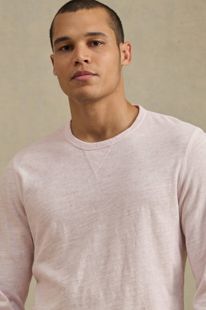 A person with short hair wears the ZANE TEE by Velvet by Graham & Spencer—a light pink, textured slub crew neck—while standing against a plain neutral background.