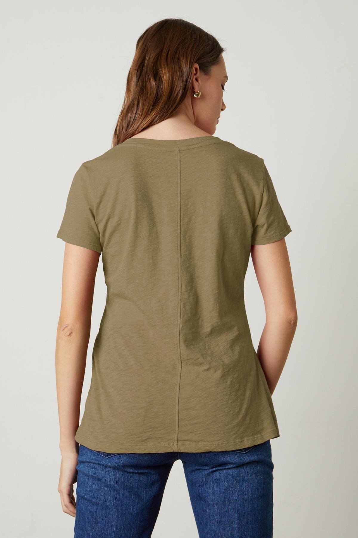 The back view of a woman wearing a Velvet by Graham & Spencer LILITH COTTON SLUB V-NECK TEE, showcasing her cool tomboy style.-35782982467777