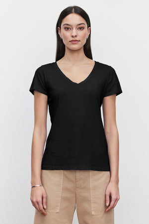 A woman sporting a casual tomboy style with a black LILITH COTTON SLUB V-NECK TEE by Velvet by Graham & Spencer.