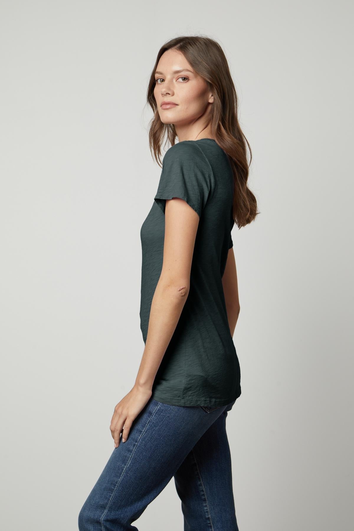   A woman rocking a tomboy style in a dark green Velvet by Graham & Spencer LILITH COTTON SLUB V-NECK TEE and jeans. 