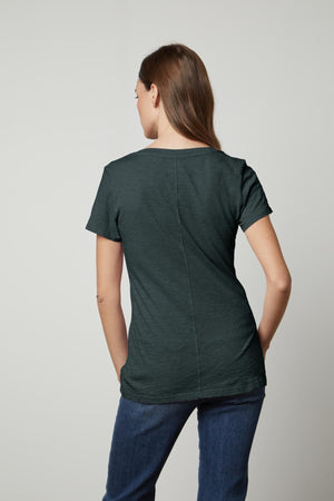 The back view of a woman wearing jeans and a green Velvet by Graham & Spencer LILITH COTTON SLUB V-NECK TEE.