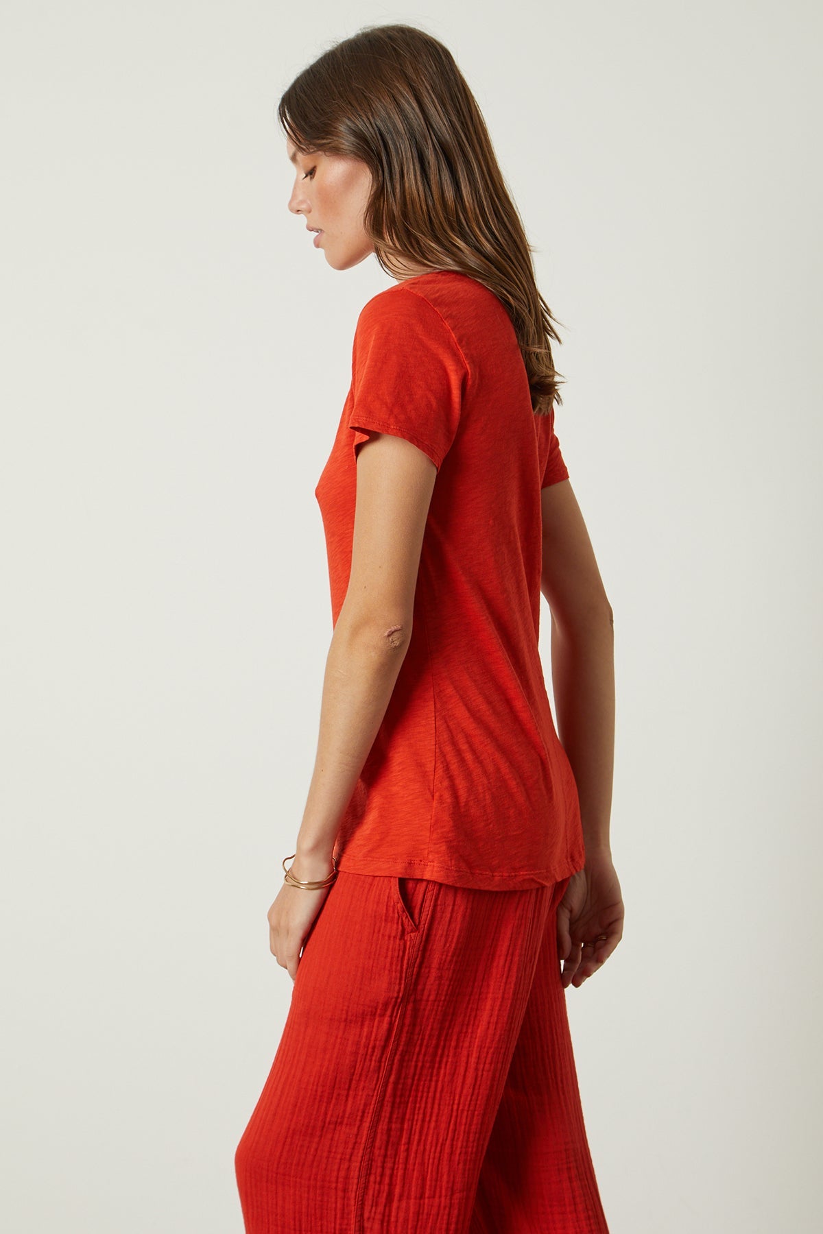   a woman wearing a red Velvet by Graham & Spencer LILITH COTTON SLUB V-NECK TEE t - shirt and wide leg pants. 