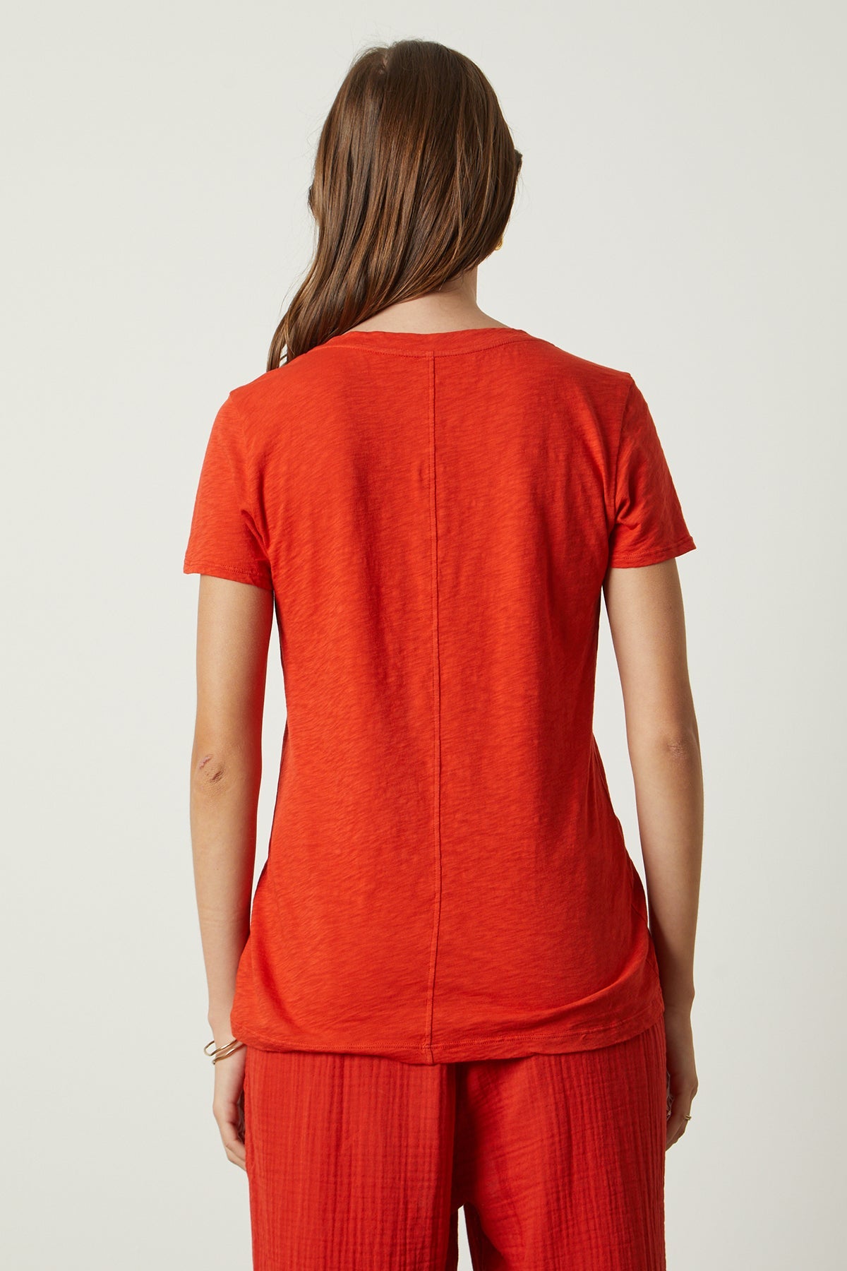 The sentence: "the back view of a woman wearing a Velvet by Graham & Spencer LILITH COTTON SLUB V-NECK TEE.-26630611304641