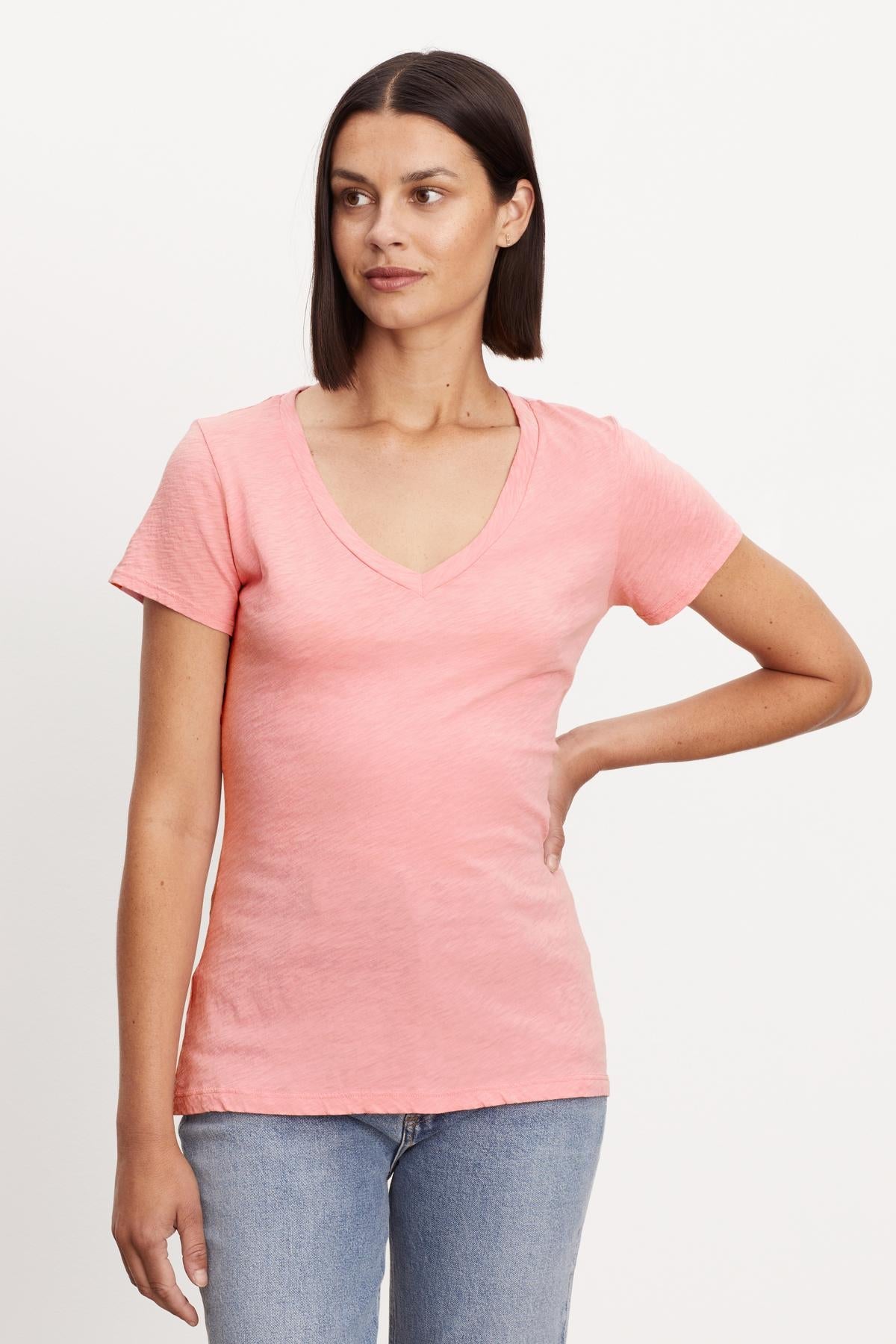   A woman sporting a preppy tomboy style in a pink LILITH COTTON SLUB V-NECK TEE by Velvet by Graham & Spencer. 