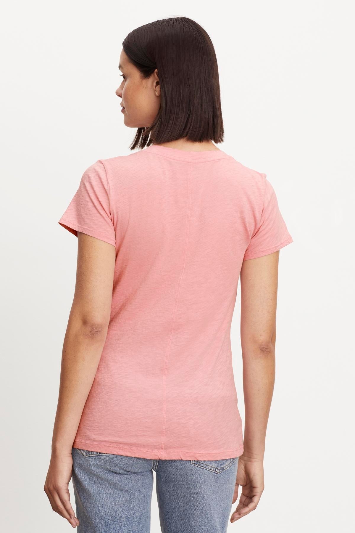   The woman is wearing a pink LILITH COTTON SLUB V-NECK TEE with a tomboy style by Velvet by Graham & Spencer. 