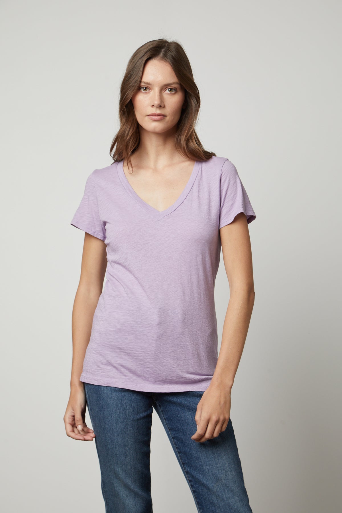   A woman sporting a preppy tomboy style in a lavender LILITH COTTON SLUB V-NECK TEE by Velvet by Graham & Spencer. 