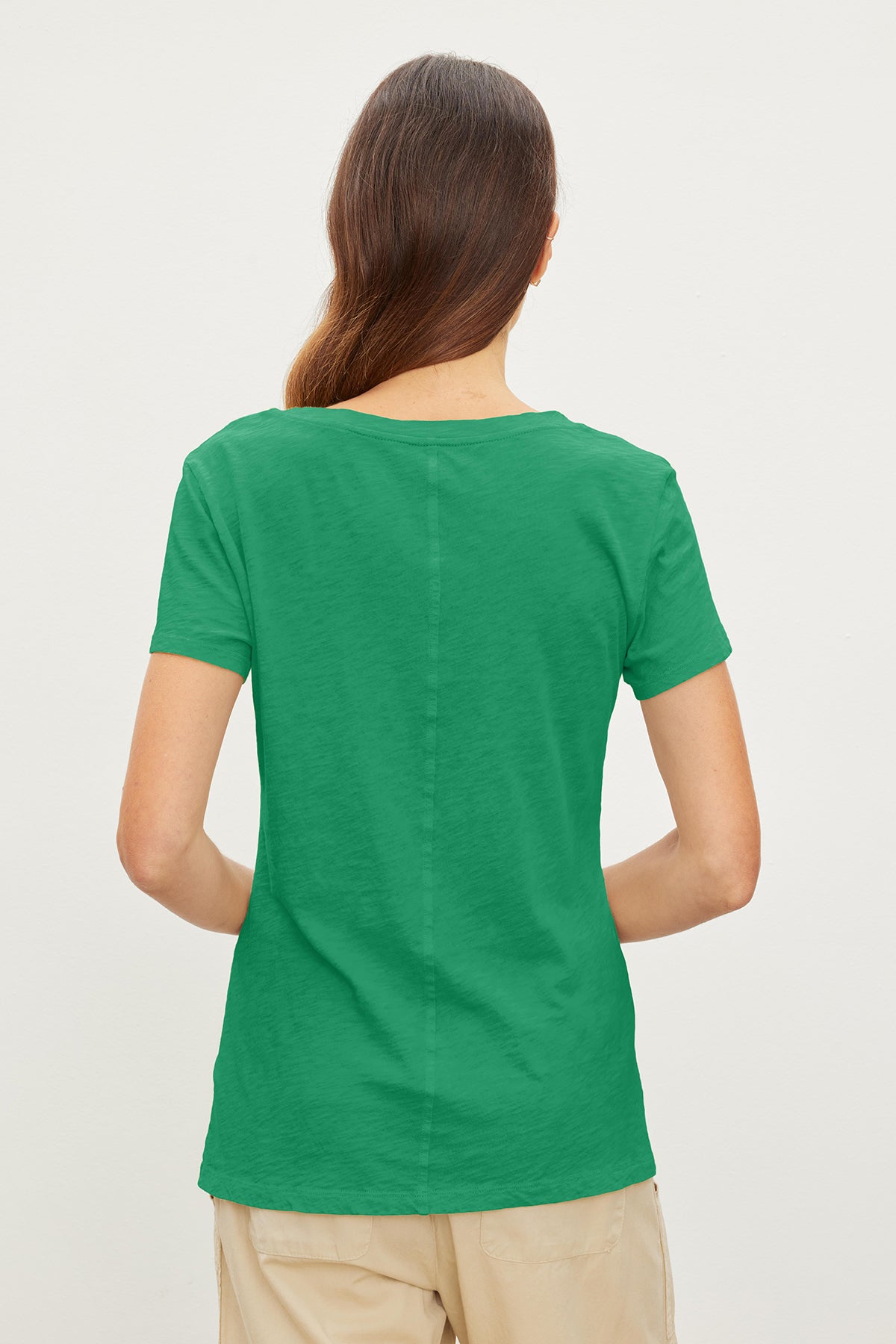 Rear view of a woman wearing a Velvet by Graham & Spencer LILITH COTTON SLUB V-NECK TEE and beige pants, standing against a white background.-36910215102657