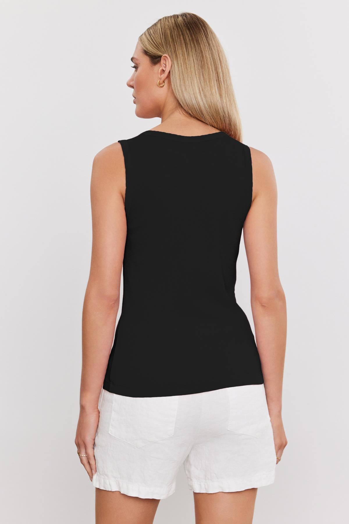 A woman with straight, long blonde hair is shown from the back, wearing a MAXIE RIBBED TANK TOP by Velvet by Graham & Spencer and white shorts against a plain white background.-37241154404545