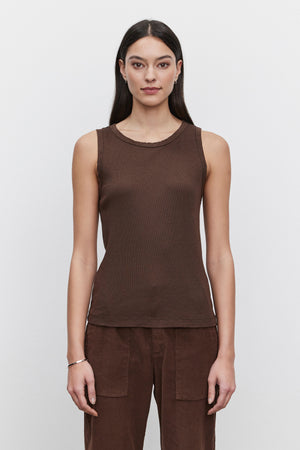 A person with long dark hair, wearing a sleeveless MAXIE RIBBED TANK TOP in brown from Velvet by Graham & Spencer and matching brown pants made from soft textured fabric, stands against a plain white background.